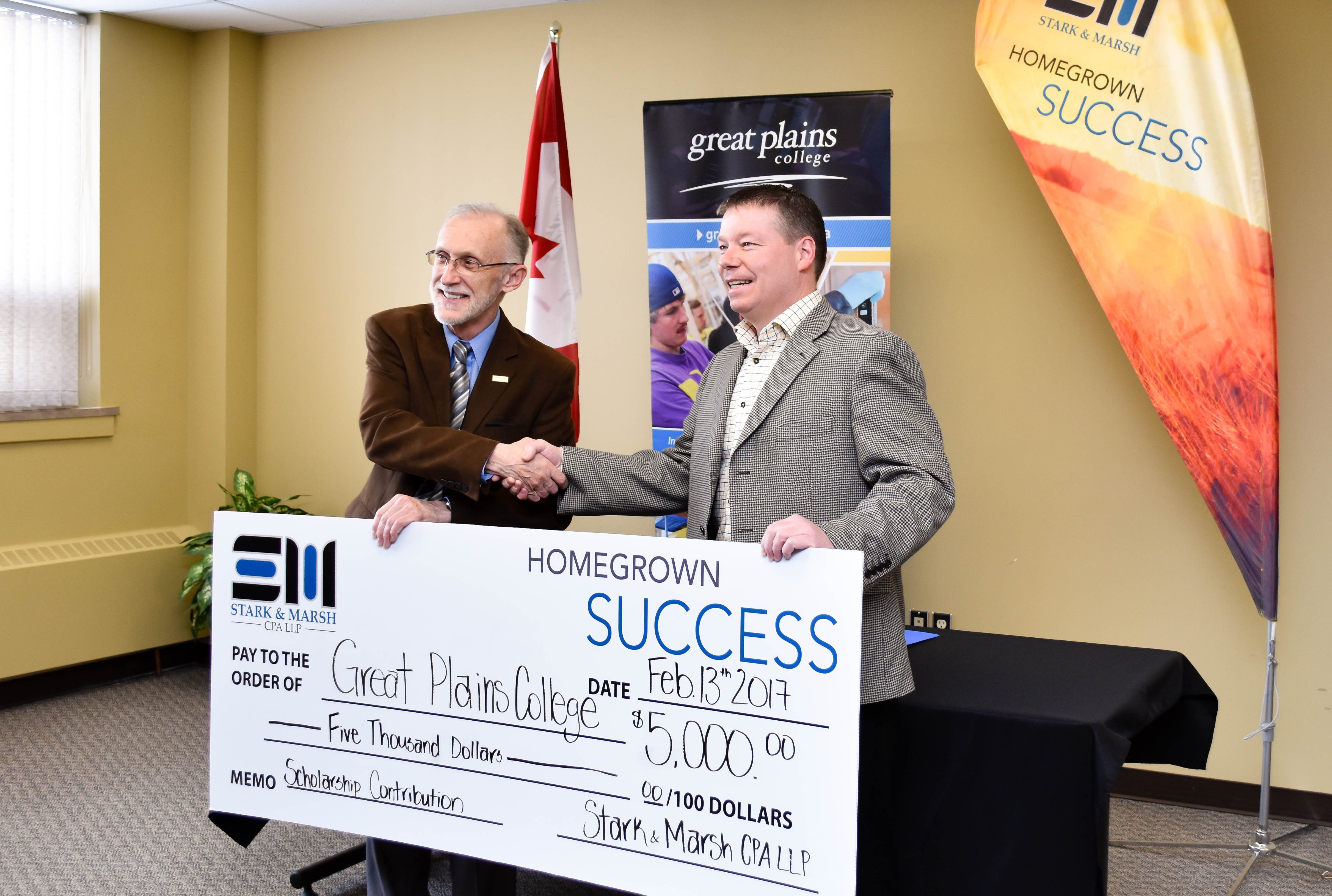 Elden Moberg, CEO of Stark & Marsh CPA LLP, presents David Keast, president of Great Plains College with a $5,000 cheque.