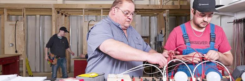 Electrician student and instructor looking at a light board in the electrical shop