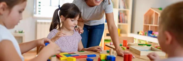 Early childhood educator working with kids around a play mat