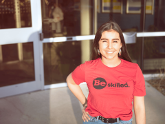 woman posing with a read shirt reading "be skilled"